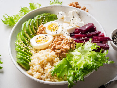 Buddha bowl, balanced food, vegetarian menu. Grey marble table, side view. Eggs, avocado, salad lettuce, bulgur, beetroot, tofu